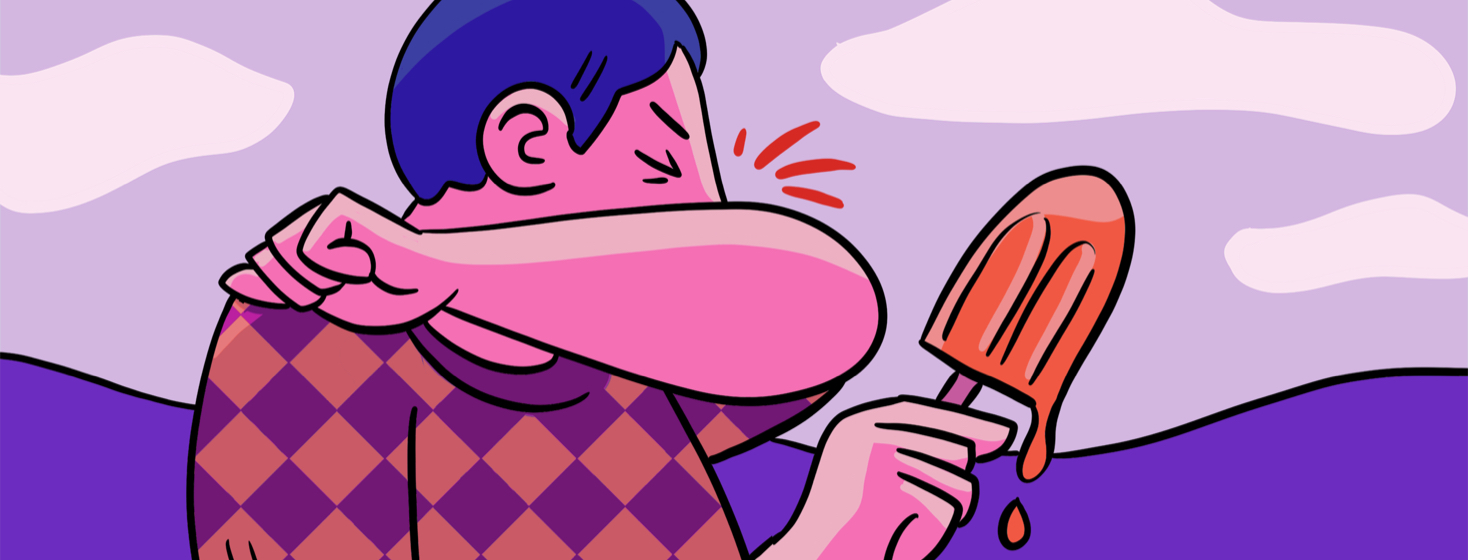 A man coughing into his elbow while holding a popsicle